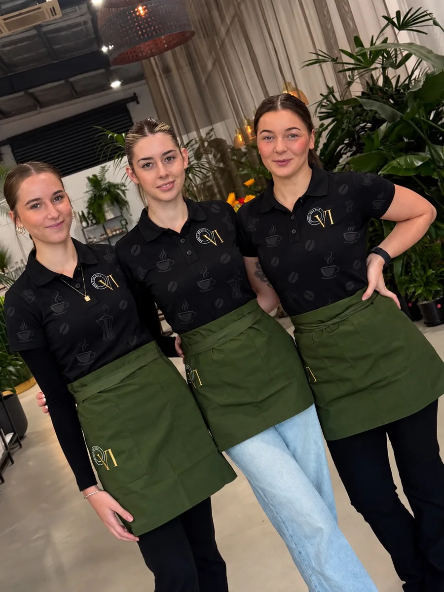 Café staff in black shirts and green aprons